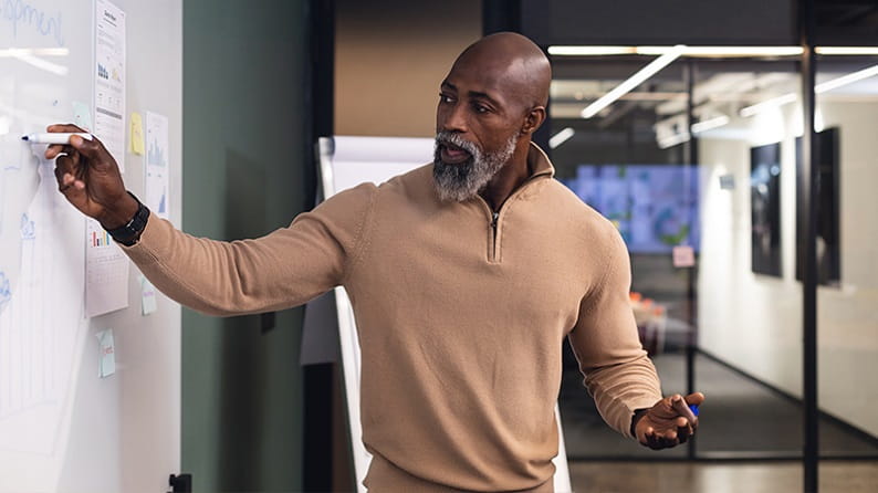 a black man leading a whiteboard session